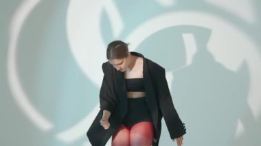 Siyah elbiseli genç kadın beyaz arka planda çağdaş dans ediyor..