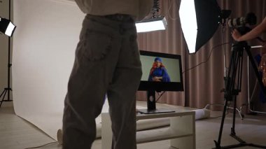 Günlük yaşam tarzı konsepti. Yetişkin bir kadın stüdyoda, şık kıyafetler içinde fotoğrafçı ve asistanlarla fotoğraf çekimine katılıp kıyafet seçiyor..