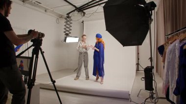 Günlük yaşam tarzı konsepti. Yetişkin bir kadın stüdyoda kalıyor. Süslü giysiler içinde kadın modeller profesyonel bir stüdyoda fotoğrafçı ve asistanlarla makyaj yapıyor..
