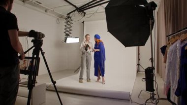 Günlük yaşam tarzı konsepti. Genç bir kadın stüdyoda zaman geçiriyor. Süslü giysiler içinde kadın manken. Profesyonel bir stüdyoda fotoğrafçıyla fotoğraf çekimine katılıyor..