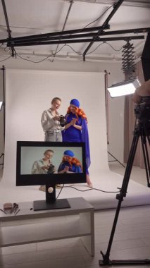 Günlük yaşam tarzı konsepti. Genç bir kadın stüdyoda zaman geçiriyor. Süslü giysiler içinde kadın manken. Profesyonel bir stüdyoda fotoğrafçıyla fotoğraf çekimine katılıyor..