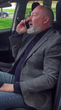 Direksiyon başında akıllı telefondan konuşan yaşlı bir adam. Görüntü odaklanmayı ve bağımsızlığı iletirken aynı zamanda işe normal bir ortamda gidip geliyor. Dikey video