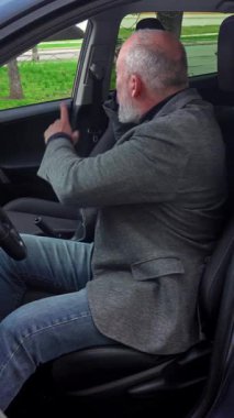 Direksiyon başında akıllı telefondan konuşan yaşlı bir adam. Görüntü odaklanmayı ve bağımsızlığı iletirken aynı zamanda işe normal bir ortamda gidip geliyor. Dikey video