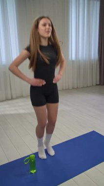 Günlük yaşam tarzı konsepti. Genç kız antrenmanlarda vakit geçiriyor, spor giyimli kız amigo kız antrenmanlarına katılıyor ısınma egzersizleri yapan kız yoga minderinde duruyor. Dikey video