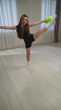 Günlük yaşam tarzı konsepti. Genç kız antrenmanlarda vakit geçiriyor, spor giyimli kız ponpon kız antrenmanlarına katılıyor, ponpon kızlarla dans egzersizleri yapıyor. Dikey video