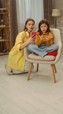 Günlük yaşam tarzı konsepti. Genç kız akşam yemeğini evde geçiriyor. Oturma odasında annesiyle oturuyor. İnternetten akıllı telefondan alışveriş yapıyor..