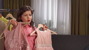 Günlük yaşam tarzı konsepti. Genç kız evde vakit geçiriyor, kız blogcu kız akıllı telefondan video kaydediyor, kamera karşısında konuşuyor elbise seçiyor, gülümsüyor, olumlu ifade veriyor..