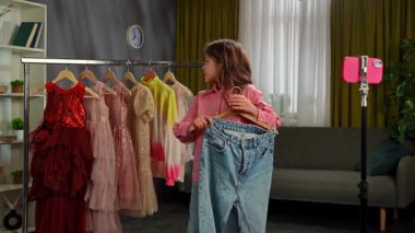 Günlük yaşam tarzı konsepti. Genç kız evde vakit geçiriyor, kız blogcu kız akıllı telefondaki videoyu kaydediyor, kamerada konuşmak kıyafetleri gösteriyor, gülümsüyor, olumlu ifade veriyor..