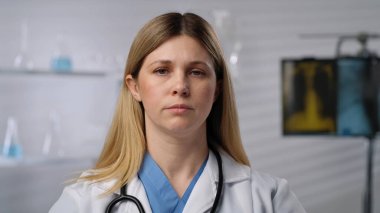 Bir kadın doktor ciddi bir ifadeyle tıbbi ortamda gösterilir, profesyonelliğini yansıtır..