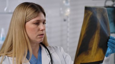 Bir doktor, teşhis ve hasta bakımına odaklanarak, tıbbi bir ortamda röntgen görüntüsünü yakından inceler..