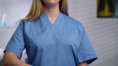 Eldiven giyen bir sağlık uzmanı, içinde beyaz haplar bulunan bir paketi klinik ortamda tutuyor. Yaklaşın, ağır çekim.