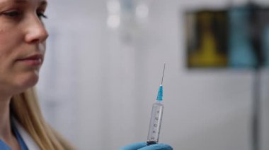 Bir sağlık uzmanı, klinik ortamda rutin bir tıbbi görevi tasvir eden bir iğneyi hassasiyetle hazırlar. Yaklaşın, ağır çekim.