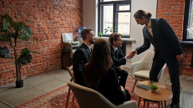 Modern bir ofiste, takım çalışması ve işbirliği üzerine kurulu, tuğladan bir duvarı olan profesyonel bir iş toplantısı gerçekleşiyor..