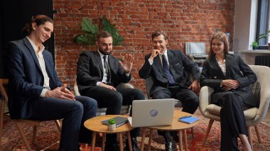 Resmi giyinmiş bir grup profesyonel, modern bir ofiste, duvarları tuğlalı bir ofiste toplantı yapıyorlar..