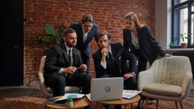 Çağdaş bir ofiste dizüstü bilgisayardaki verileri analiz eden bir grup profesyonel iş toplantısına katıldı..