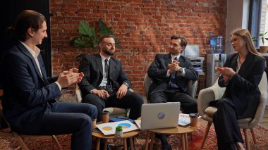 Modern bir ofis ortamında masanın etrafında oturan dört meslektaşı profesyonel bir iş toplantısındalar..