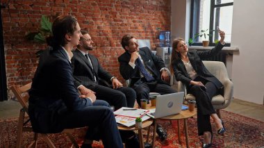 Bir iş ekibi modern ofis ortamında toplantı yapıyor. Bir kadın iş arkadaşlarıyla selfie çekiyor..