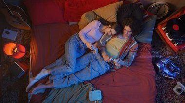 Birkaç yatak, gitar, kitap ve lambayla dekore edilmiş rahat bir odada retro oyun seansının keyfini çıkarmak. Üst çekim