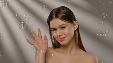 Mutlu bir kadın ışıldayan sabun köpükleriyle çevrili, neşeli ve kaprisli bir sahne yaratıyor..