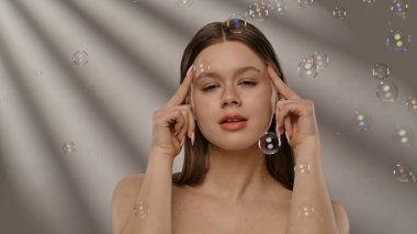 Etrafı kabarcıklarla çevrili bir kadın neşeli ve kaprisli bir sahne yaratıyor..