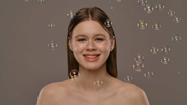 Gülümseyen bir kadın ışıldayan sabun köpükleriyle çevrili, neşeli ve kaprisli bir sahne yaratıyor..