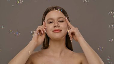 Etrafı kabarcıklarla çevrili bir kadın neşeli ve kaprisli bir sahne yaratıyor..