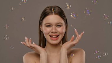 Gülümseyen bir kadın ışıldayan sabun köpükleriyle çevrili, neşeli ve kaprisli bir sahne yaratıyor..