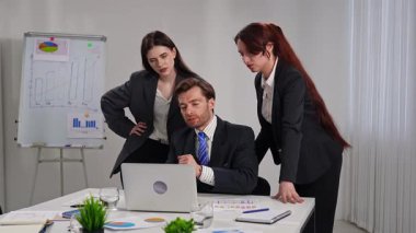 Modern bir ofiste yapılan toplantı sırasında resmi giyinmiş üç profesyonelden oluşan bir grup iş raporlarını inceliyor..