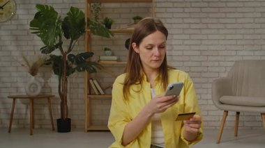 Sarı tişörtlü genç bir kadın, elinde pasaport ve kağıtla video görüşmesi yaparken gülümsüyor..