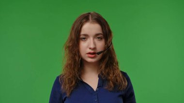 Kulaklıklı genç bir kız canlı yeşil bir arka planda dikkatle dinliyor gibi görünüyor..