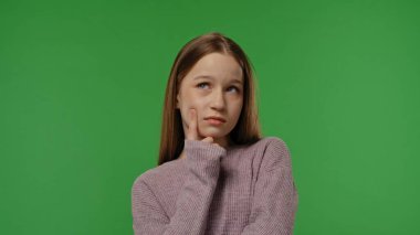 Gençlik duyguları konsepti. Genç kız kameraya konsantre yüzüyle poz veriyor, düşünüyor, krom anahtar yeşil ekran arka plan modelinde izole edilmiş..