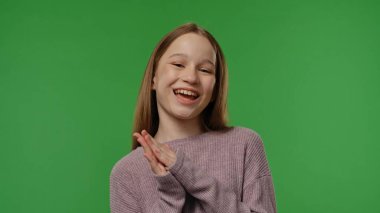 Gençlik duyguları konsepti. Kameraya poz veren ve alkışlayan genç kız, gülümseyen olumlu ifade, krom anahtar yeşil ekranda izole edilmiş arka plan modeli..