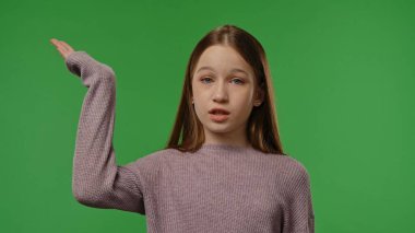 Gençlik duyguları konsepti. Kameraya gülümseyen ve avuç içini gösteren genç kız, pozitif ifade, krom anahtar yeşil ekran arka plan modelinde izole edilmiş..
