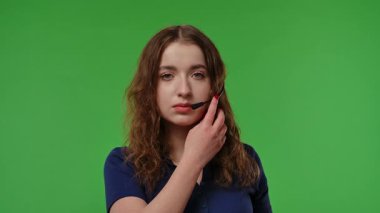 Kulaklıklı genç bir kız canlı yeşil bir fon karşısında dikkatle dinliyor gibi görünüyor. Yavaş çekim