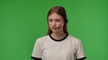 Kulaklıklı genç bir kız canlı yeşil bir fon karşısında dikkatle dinliyor gibi görünüyor. Yavaş çekim