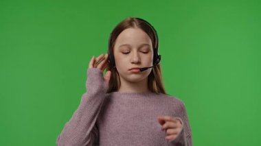 Kulaklıklı genç bir kız canlı yeşil bir fon karşısında dikkatle dinliyor gibi görünüyor. Yavaş çekim