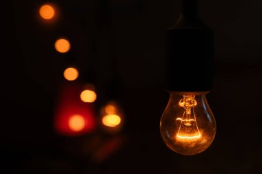 Parlayan ampullerin görüntüsü, karanlık ve çevresel bir ortamda sıcak bir parıltı bırakıyor. Kapat.