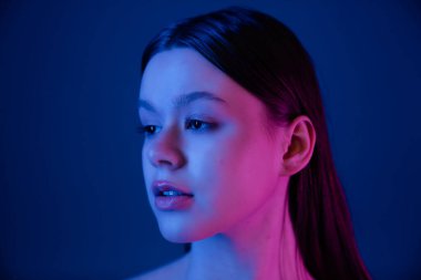 Çarpıcı bir portre, zıt mavi ve pembe ışıklarla yıkanmış bir kadının huzurlu ifadesini vurgular..