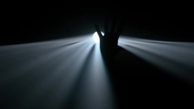 Sisli karanlık stüdyoda sahne ışıklarının içindeki kişi. Parlak soğuk spot ışıkları, karanlıkta parlayan profesyonel ışıklandırma ekipmanları, dumanla ve ışıkla oynayan el silueti..