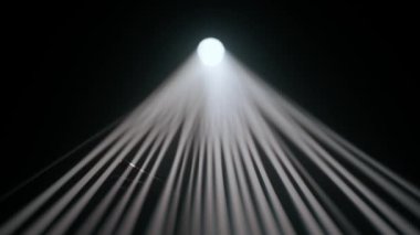 Sisli karanlık stüdyoda sahne ışıklarının içindeki kişi. Parlak beyaz spot ışıkları, karanlıkta parlayan profesyonel ışıklandırma ekipmanları, el silueti dumana ve ışık ışınlarına dokunarak oynuyor..