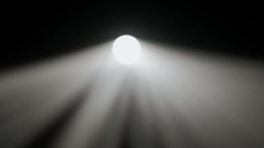 Sisli karanlık stüdyoda sahne ışıklarının içindeki kişi. Parlak beyaz spot ışıkları, karanlıkta parlayan profesyonel ışıklandırma ekipmanları, dumanla ve ışıkla oynayan el silueti, kapat..