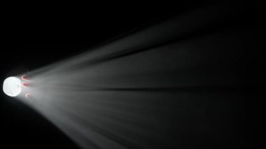 Sisli karanlık stüdyoda sahne ışıklarının içindeki kişi. Parlak beyaz spot ışıkları, sol taraftan karanlıkta parlayan profesyonel ışıklandırma ekipmanları, dumanla ve ışıkla oynayan el silueti.