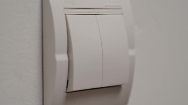 Bir el loş ışıklı bir odada, sakinleştirici mavi bir renkle yıkanmış bir ışık düğmesini kapatmak için uzanır. Yaklaşın, ağır çekim.