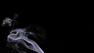 Büyüleyici bir görüntü, narin, kıvrımlı duman desenlerini siyah arka planda gösteriyor, kontrastı ve akıcılığı vurguluyor. Yavaş çekim