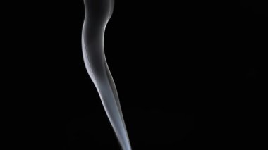 Zifiri karanlık bir zemine doğru zarif bir duman girdabı yükseliyor, basitlikteki güzelliği vurguluyor. Yavaş çekim