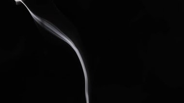 Narin bir duman zerafetle karanlık bir zemine doğru yükselir ve pürüzsüz, akışkan şeklini ortaya çıkarır. Yavaş çekim