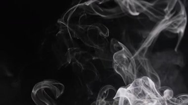Hassas duman girdapları gizemli ve zarif görünen karanlık bir arkaplan karşısında ruhani bir desen oluşturur. Yavaş çekim