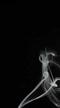 Büyüleyici duman girdapları narin, akışkan desenler, karanlık bir zemin üzerine kurulmuş zarafet ve gizemi somutlaştırıyor. Yavaş çekim, dikey video