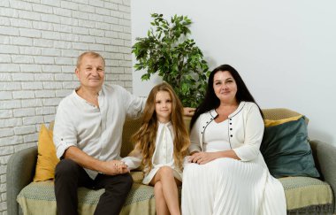 Sıcak ve davetkar bir aile portresi. Sevilen beş kişi. Hepsi de neşeyle şık beyaz kıyafetler giymişler.