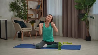 Genç bir kadın su içmek için yoga seansına ara veriyor. Odaklanma ve su kaybını arttırıyor..